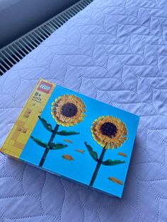 the book is on top of the bed with two sunflowers painted on it