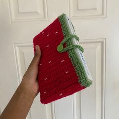 a hand holding a red and green crocheted cloth