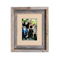 the family is posing for a photo in front of a white wall with an old wooden frame