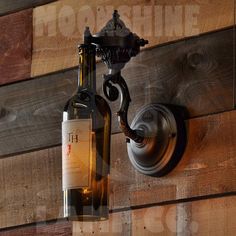 a bottle of wine is hanging on the wall next to a light fixture and wood planks