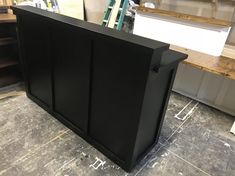 a black cabinet sitting on top of a hard wood floor next to a wooden counter