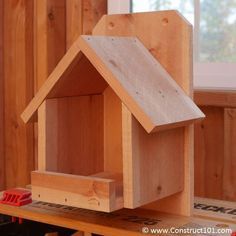 a wooden birdhouse sitting on top of a workbench in a wood shop