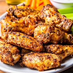 some chicken wings are on a plate with carrots and celery