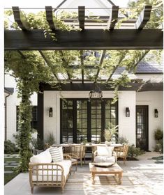 an outdoor living area with couches, tables and chairs under a pergolated roof