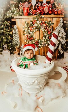 a baby is sitting in a bathtub surrounded by christmas decorations and candy canes