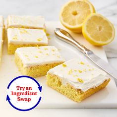 there are lemon squares with icing on the plate next to some sliced lemons