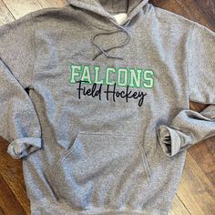 Show your team pride with our cozy hooded sweatshirt. Featuring your team mascot embroidered in a bold two-color varsity font and the name of your sport underneath, this sweatshirt combines style and comfort. Made from a soft cotton-poly blend with a roomy front pocket and adjustable drawstrings, it's perfect for game days or casual wear. Available in multiple sizes--gear up and support your team with pride! If there is a sport you would like that is not on the list just reach out and I can work Sportswear Fan Gear Hoodie Sweatshirt, Team-colored Winter Sports Hoodie, Field Hockey Sweatshirts, Athletic Fonts, Hockey Gear, Team Sweatshirts, Team Mascots, Field Hockey, True Red