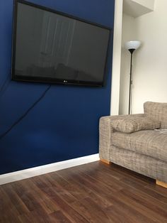 a flat screen tv mounted to the side of a blue wall in a living room