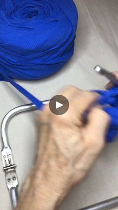 a hand holding a pair of scissors next to a blue rope