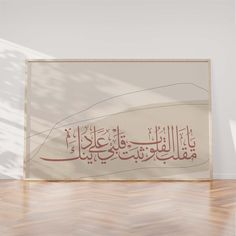 an arabic calligraphy is displayed on the floor in front of a white wall and wooden floors