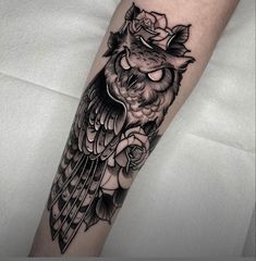 a black and white owl with roses on its head is sitting on the arm tattoo