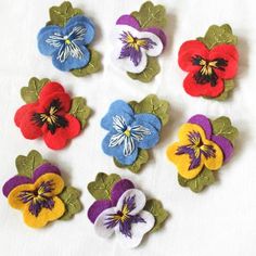 several different colored flowers on a white surface