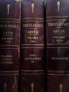 three red books sitting on top of each other in front of a white wall with gold lettering