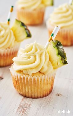 cupcakes with white frosting and green leaves on top are sitting on a table