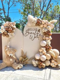 a teddy bear sitting in front of a welcome sign made out of eggs and shells