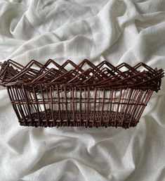 three woven baskets sitting on top of a white cloth covered bed sheet, with one empty basket in the middle