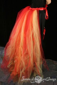 a woman wearing a red and orange tulle skirt with a black shirt underneath her