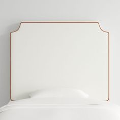 a white bed with an orange trim around the headboard