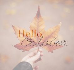 a person holding a leaf with the words hello october written on it