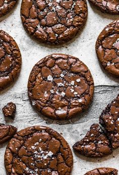 chocolate cookies with powdered sugar on top are lined up on a sheet of parchment paper