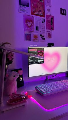 a desk with a computer, keyboard and mouse in front of a purple light on the wall