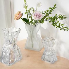 three glass vases with flowers in them on a table