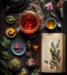 an open book sitting on top of a table next to bowls filled with flowers and herbs