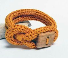 an orange rope bracelet with a wooden block on it and a piece of wood sticking out of the clasp