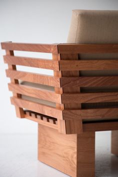 a wooden chair sitting on top of a white floor next to a brown couch cushion