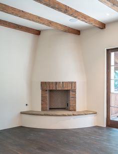 an empty room with a fireplace and wooden beams