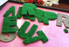 the letters are made out of grass and have been cut into small pieces with scissors