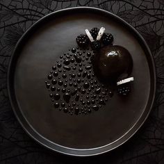 a black plate topped with an apple and two pieces of fruit on top of it