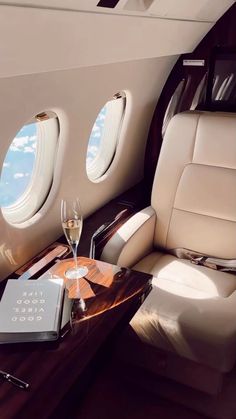 the interior of an airplane with two wine glasses and a book on a wooden table