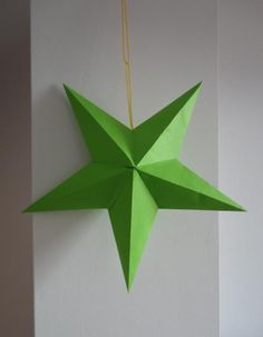 a green origami star hanging from a wall