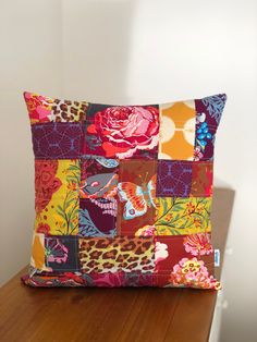 a colorful patchwork pillow sitting on top of a wooden table