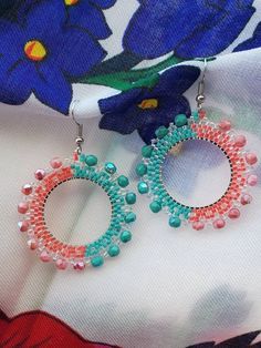 two pairs of beaded hoop earrings sitting on top of a flowered fabric piece