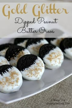 some cookies with white and black frosting are on a plate next to the words gold glitter dipped peanut butter oreos