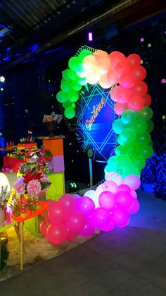 an arch made out of balloons in the middle of a room with tables and chairs