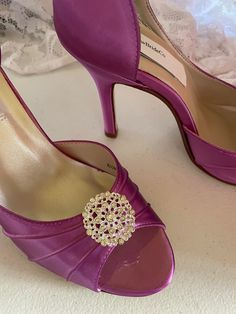 a pair of purple high heel shoes with a jeweled shoe clip on the toe