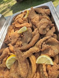 fried food in a metal pan with lemon wedges