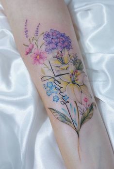 a woman's leg with flowers on it and the word love written in cursive writing