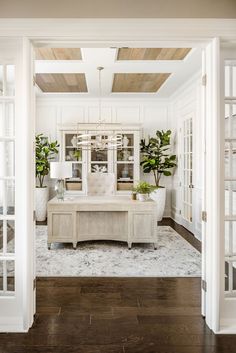 an open door leading to a dining room with white walls and wood floors, along with potted plants