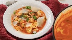 a white bowl filled with pasta and broccoli on top of a red towel