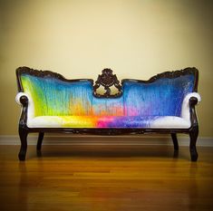 a colorful couch sitting on top of a hard wood floor next to a yellow wall