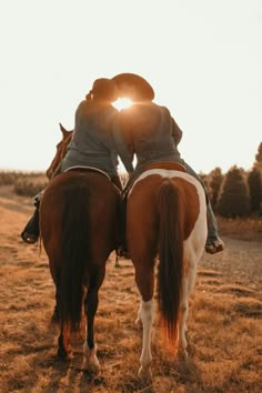 two people are kissing on the back of horses