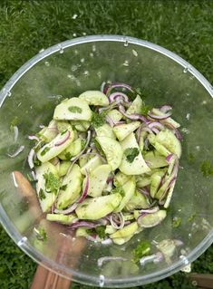 a bowl filled with cucumbers and onions on top of grass