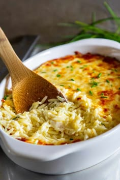 a wooden spoon in a white bowl filled with cheese and sauce on top of a table