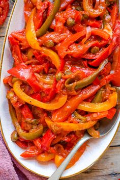 a white plate topped with red peppers next to a purple towel and silver spoon on top of a wooden table