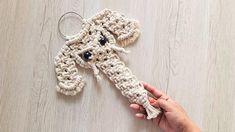 a crocheted dog keychain is being held by a woman's hand