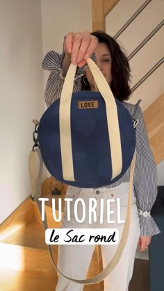 a woman holding a blue and white bag with the words love on it in french